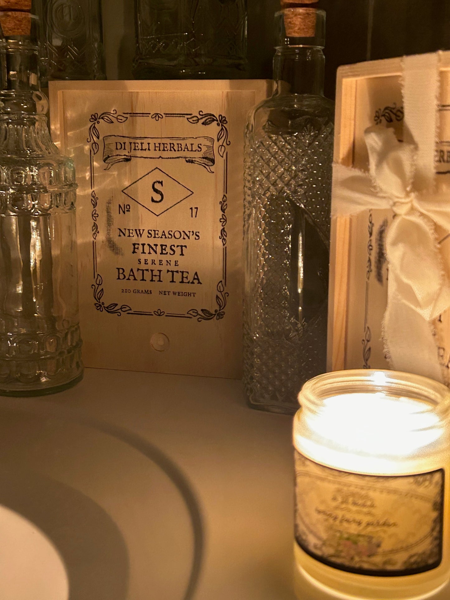 Hand-crafted Victorian romantic-inspired bath tea in a vintage style crate, and a nature-romantic inspired scented candle in the foreground.