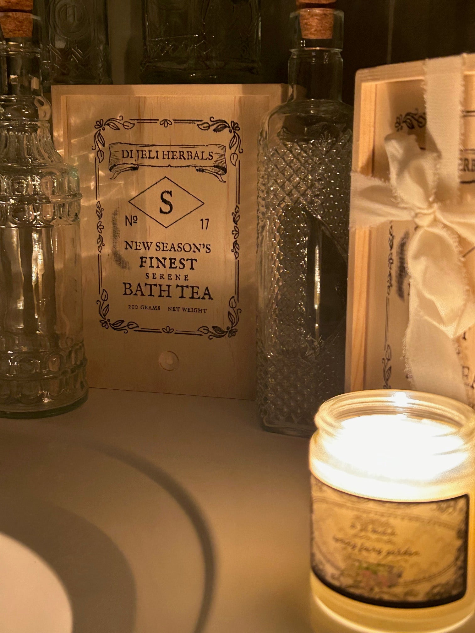 Hand-crafted Victorian romantic-inspired bath tea in a vintage style crate, and a nature-romantic inspired scented candle in the foreground.