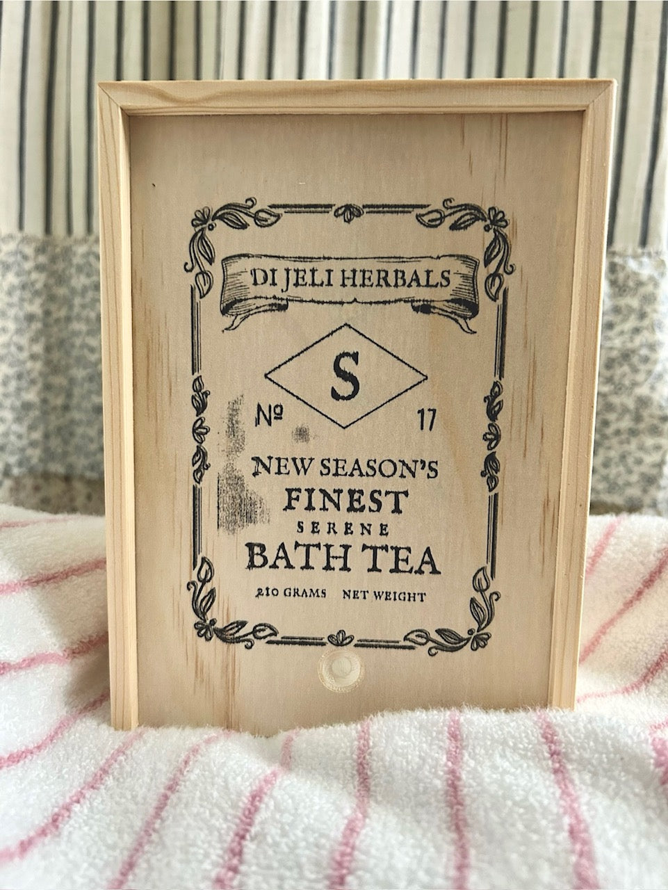 Wooden framed vintage-style tea label on a striped fabric background